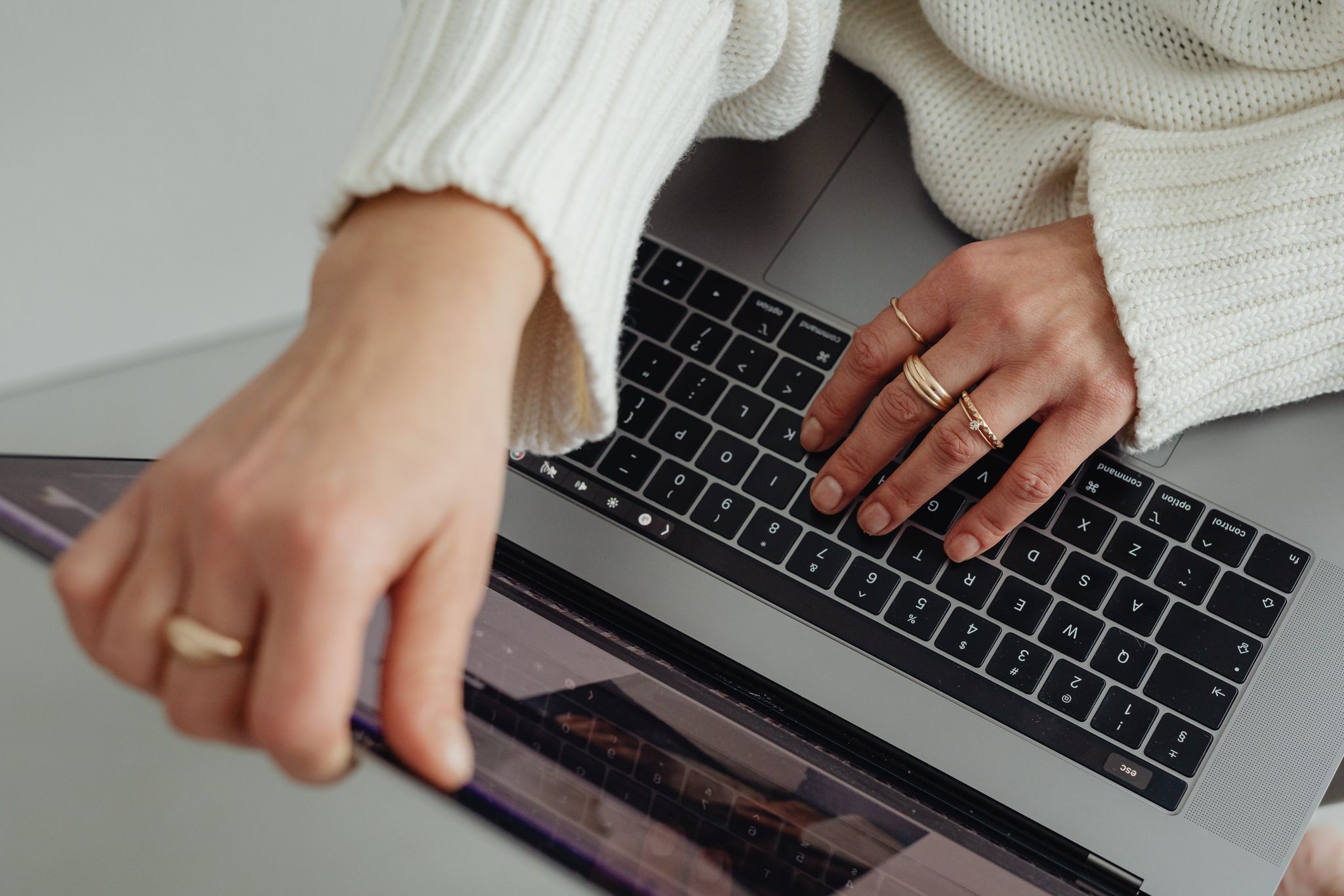 Women's hands opening Macbook with White Sweater